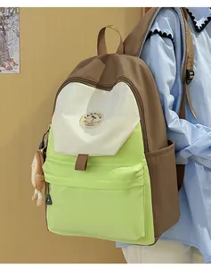 Detail eines Canvas-Rucksacks mit braunen, cremefarbenen und grünen Paneelen und Anhänger