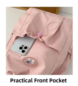 Close-up of practical front pocket with drawstring on pink school bag holding a phone