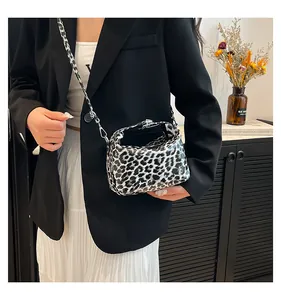 Detail view of leopard print dumpling bag with silver zipper in a lifestyle setting