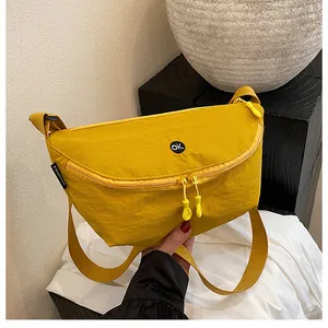 Detalle del bolso bandolera de nailon amarillo con parche OK y doble cremallera