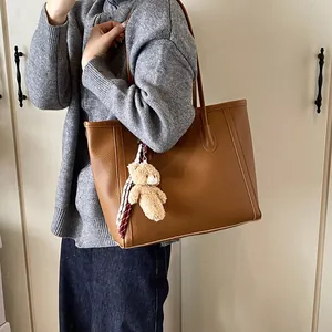 Brown large-capacity tote bag with litchi texture and cute bear pendant shown on model