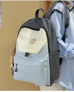 Seitenansicht des großen Color-Block-Rucksacks aus Nylon mit modischen Patches und Bärenanhänger
