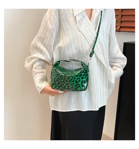 Detail shot of leopard print handbag with glossy green finish and silver metal buckles