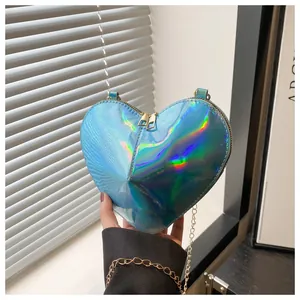 Detail of blue holographic heart-shaped bag with metallic gold chain and dual zippers