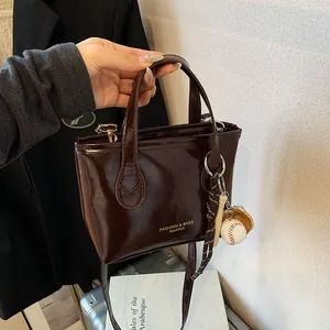 Secchiello alla moda in pelle lucida marrone scuro con manico e tracolla sottile
