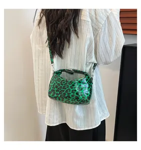 Detail view of green leopard print crossbody bag with silver hardware on a model