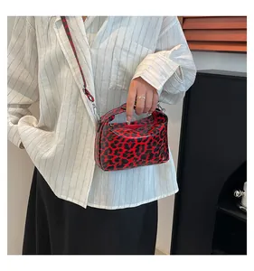Detail of red leopard print handbag with glossy leather finish and gold zipper hardware