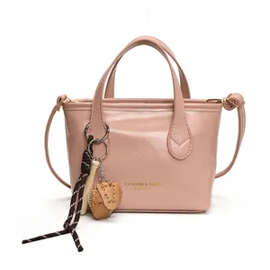 Borsa a secchiello rosa in pelle con scritte dorate e ciondolo da baseball con tracolla