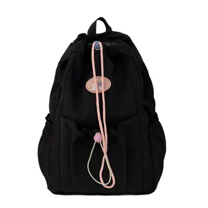 Mochila negra casual con cordón rosa y hebillas púrpuras ajustables sobre fondo blanco limpio
