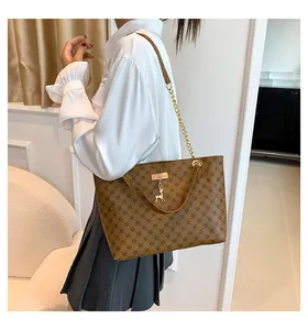 Close-up of brown printed tote bag with golden chain handle and a small deer charm