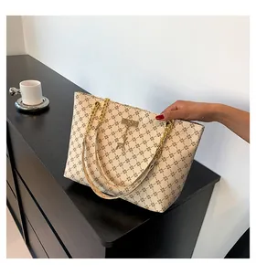 Detail of cream tote bag featuring vintage floral prints and gold chain handles