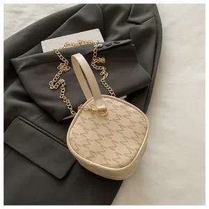 Sac à main vintage à imprimé monogramme avec bandoulière dorée sur un blazer