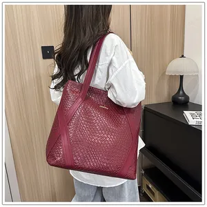Detail of burgundy woven tote bag showing fine texture and large capacity on model