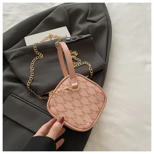 Détail du sac à main tendance avec motif M et chaîne dorée sur un blazer gris