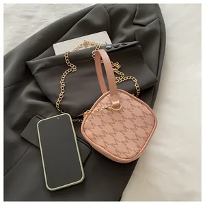 Mini sac bandoulière rose à motif monogramme avec chaîne dorée sur un blazer