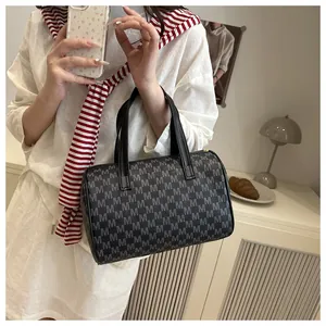 Close-up of black Boston handbag featuring white M monogram print and sturdy leather handles