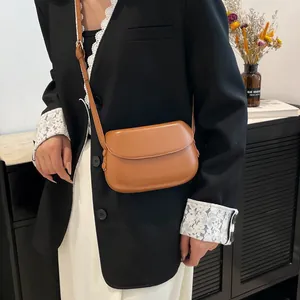 Detailed view of a vintage caramel brown saddle bag styled with a professional outfit