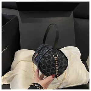 Détail d'un sac cylindrique noir vintage à imprimé M avec chaîne dorée et coffret