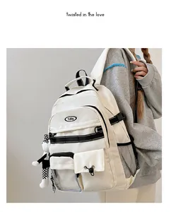 Dettaglio dello zaino bianco in stile giapponese con tasche multiple e ciondolo a scacchi