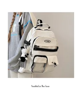 Dettaglio dello zaino bianco crema multitasche con ciondolo panda e cinghie nere eleganti