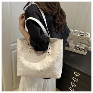 Detailed close-up of white woven tote bag texture and dual shoulder straps on a woman