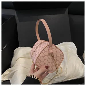Gros plan du sac cylindrique rose avec motif M et bandoulière en chaîne dorée