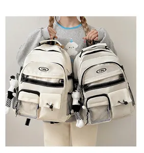 Dettaglio dello zaino in tela bianco crema con tasche multiple e accessorio a forma di panda