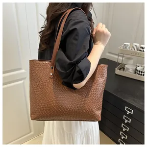 Detail of brown woven faux leather tote bag texture and reinforced silver rivets