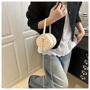 Détail d'un sac à main beige à monogramme avec chaîne dorée et imprimé élégant de lettre M