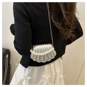 Detail of silver shell mini crossbody bag with pearl accents and gold chain strap