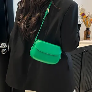 Close-up of bright green saddle bag with smooth leather texture on a black blazer