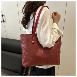 Detail of red woven tote bag showing texture, metal rivets, and spacious handle design