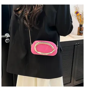 Détail du mini sac fuchsia avec grande boucle dorée et bandoulière chaîne sur un modèle