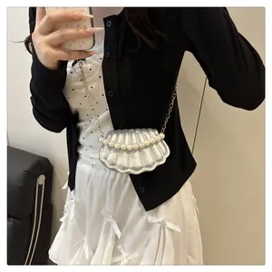 Detail showing the silver shell mini crossbody bag with pearl strap and vertical quilting