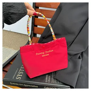 Dettaglio della borsa tote rossa con scritte dorate e manici in corda intrecciata