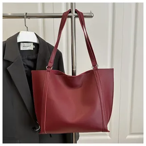 Macro detail of wine red leather tote bag showing fine stitching and metal ring buckle