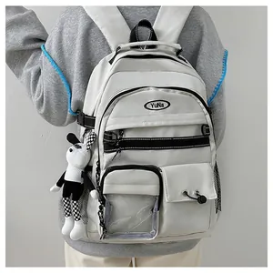 Dettaglio dello zaino scolastico in nylon bianco con multitasche e ciondolo a coniglio