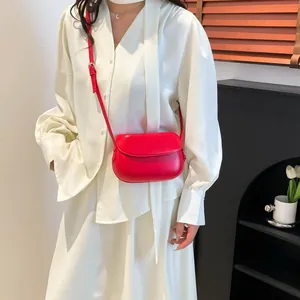 Minimalist red leather saddle bag for women shown as a stylish crossbody on white outfit