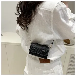 Détail d'un mini sac bandoulière noir avec texture fibre de carbone et chaîne acrylique