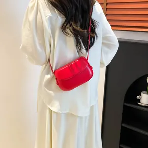 Model wearing a red vintage saddle bag made of matte leather with thin shoulder strap