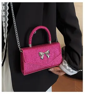 Detail of rose red sequin crossbody bag featuring a silver bow and metal chain strap