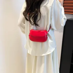 Red leather saddle crossbody bag shown from behind against a clean white outfit