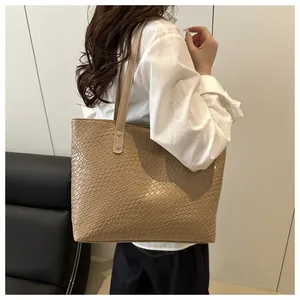 Detailed view of khaki woven tote bag showing reptile texture and silver metal rivets