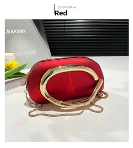 Détail de pochette rouge avec grande poignée métallique et bandoulière chaîne dorée