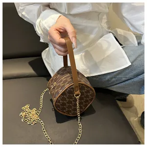 Détail d'un sac à main cylindrique à monogramme avec chaîne dorée et poignée en cuir brun
