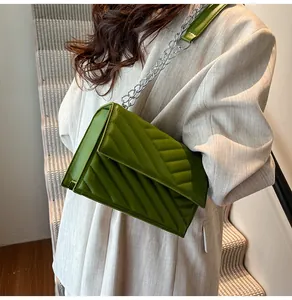 Detail der grünen V-gesteppten Ledertasche mit silberner Kette an einem Model