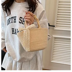 Détail du sac cabas en paille tissé à la main avec un nœud en dentelle blanche délicate