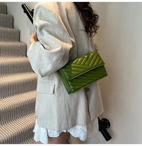 Detailansicht der grünen V-Stepptasche mit Silberkette getragen von einem Modell
