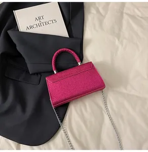 Detail of glitter pink small crossbody bag with silver chain strap on a black blazer