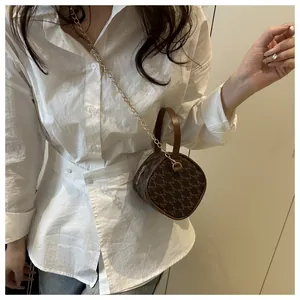 Détail du mini sac à main en cuir marron avec bandoulière dorée et motif imprimé M